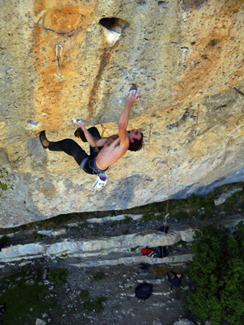 Rock climber grimaces on steep roof climb