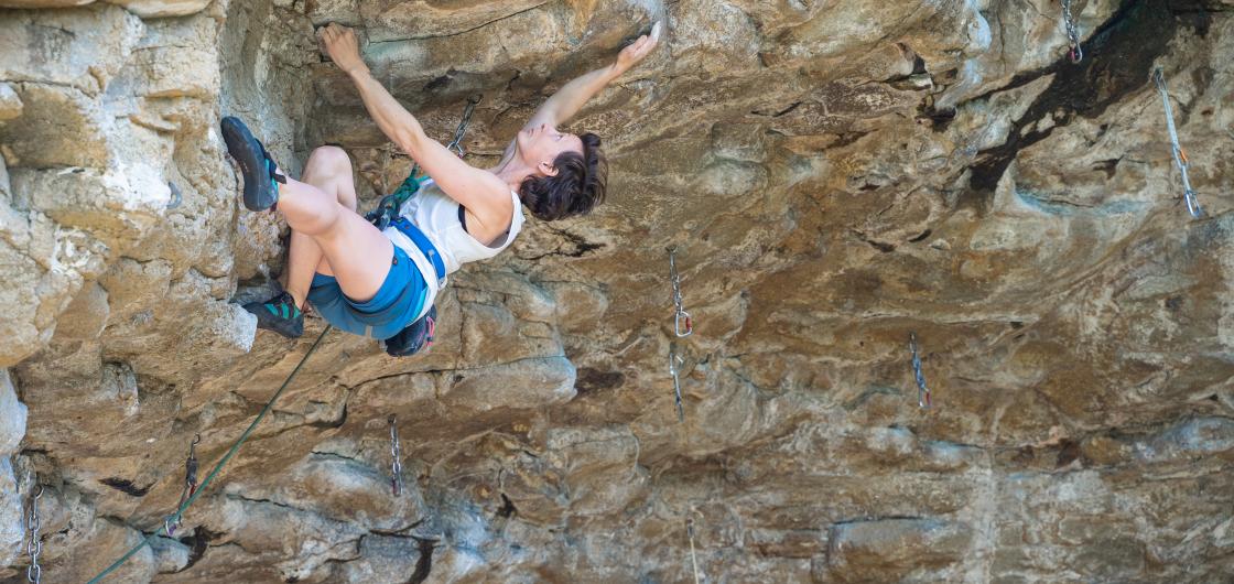 Erin Stewart attempting Rubble, at The Cave. Woman climbing steep rock.