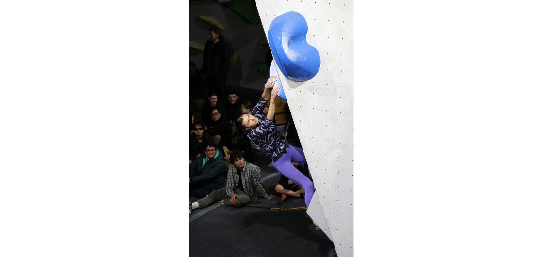 Competition climber on indoor boulder problem