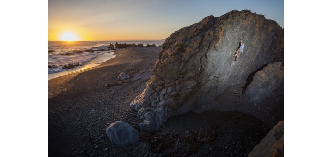 Climber on boulder at sunset.