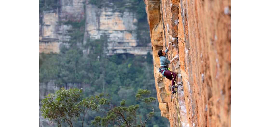 Erica climbing at Ben Trovato in the Blue Mountains. Photo: John Palmer Female rock climber on orange sandstone sport route