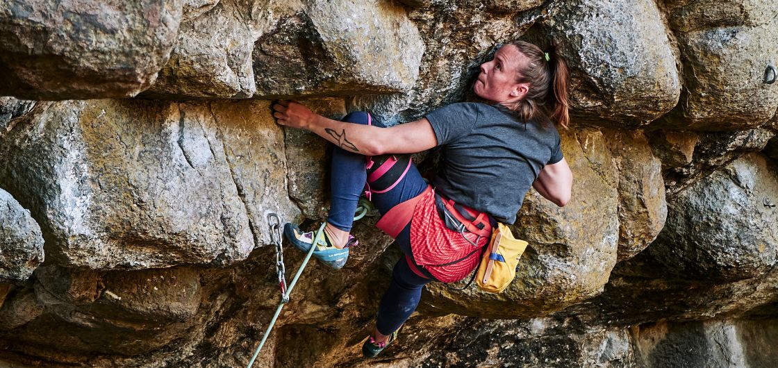 Woman climbing steep rock.