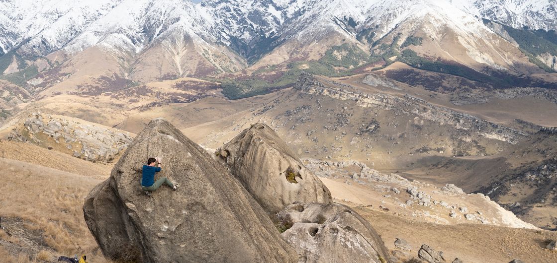 Erin Stewart climbing at Flock Hill. Photo: Rachel Musgrave Female climber on boulder in alpine setting