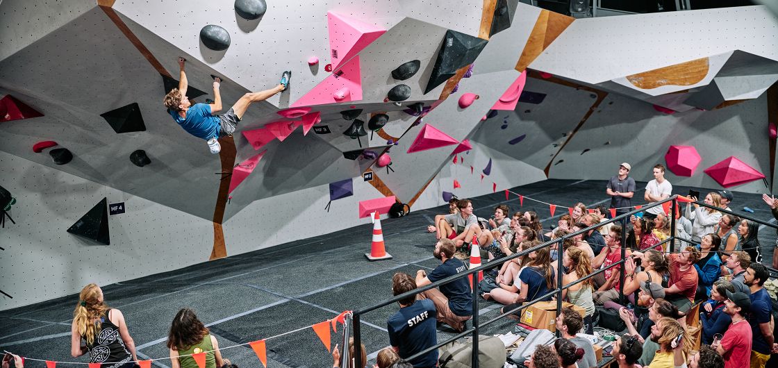 Climber on competition boulder with crowd watching