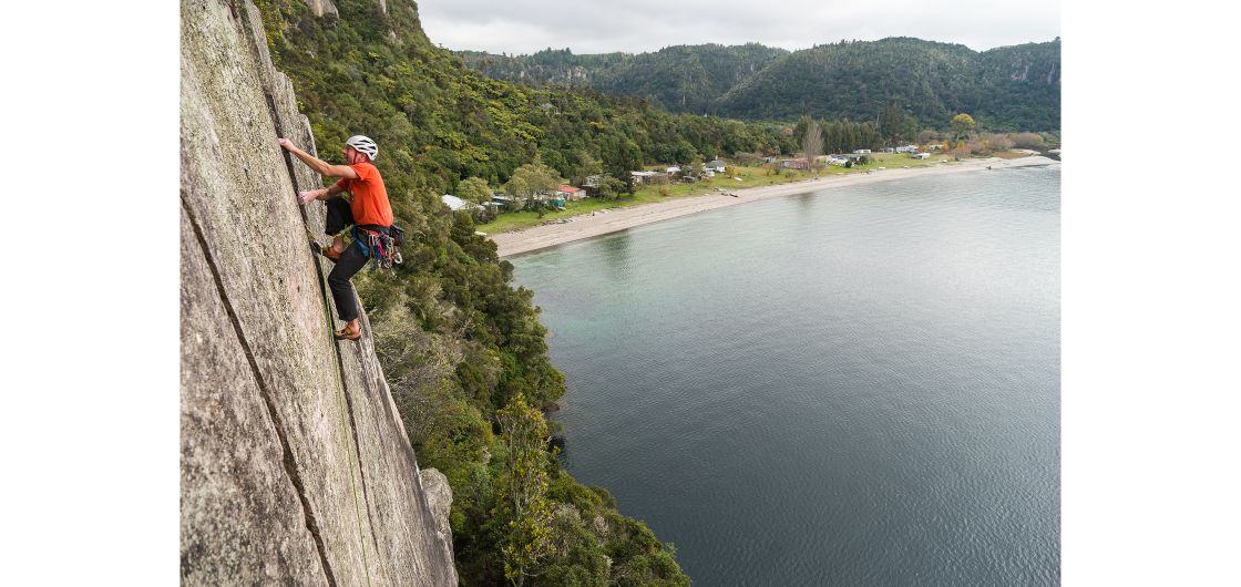 Climber on crack climb above lake