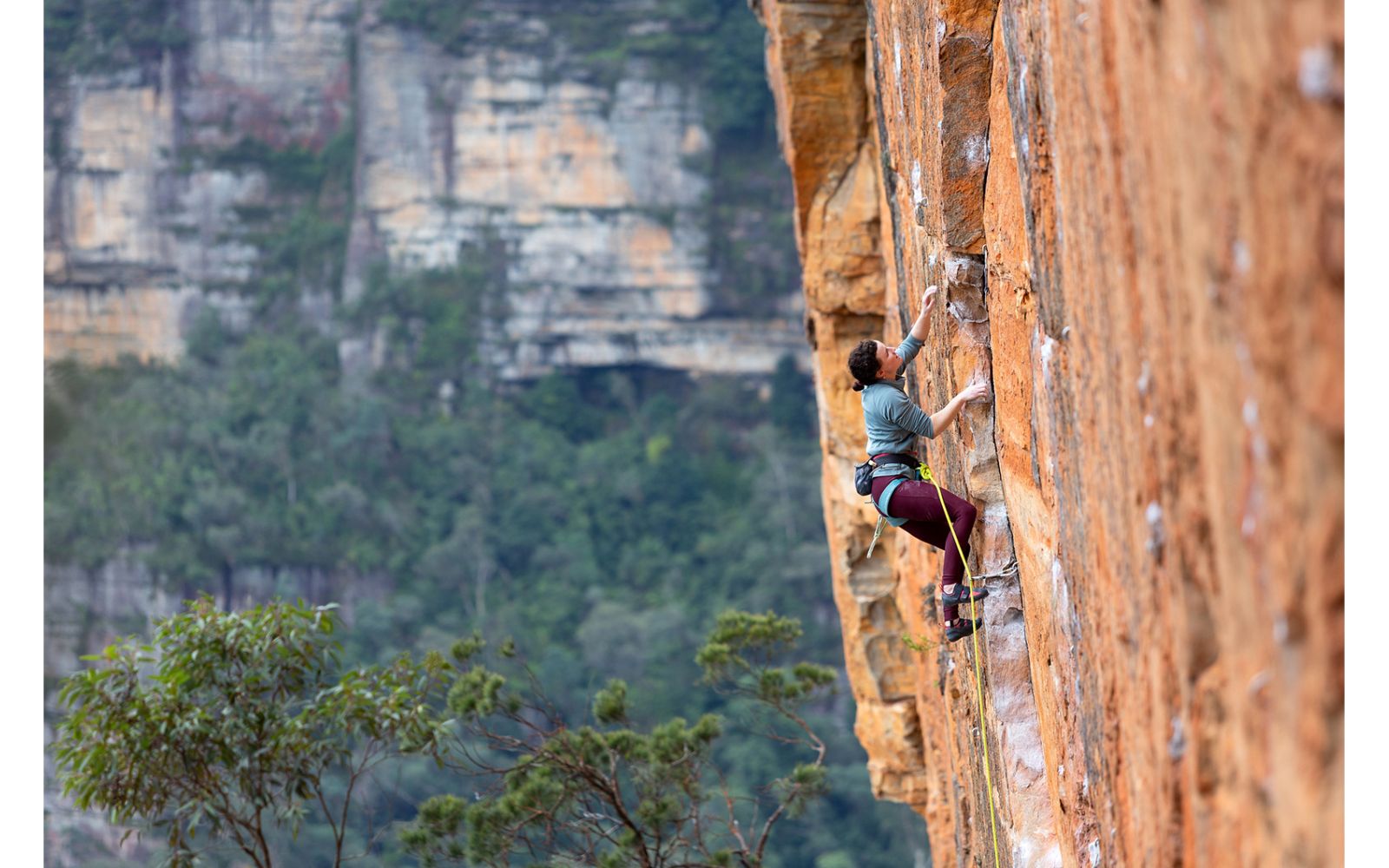 Female rock climber on orange sandstone sport route