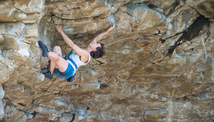 Woman climbing steep rock.