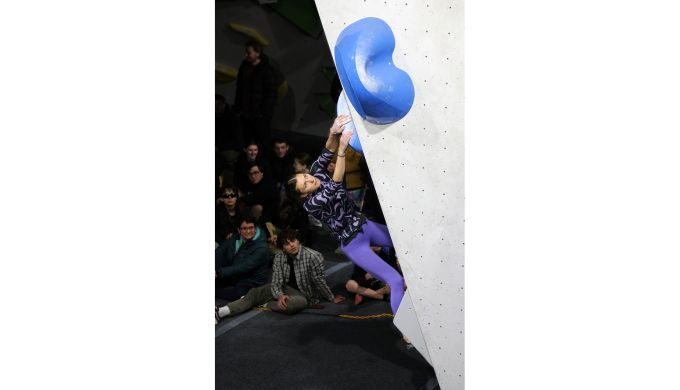 Competition climber on indoor boulder problem