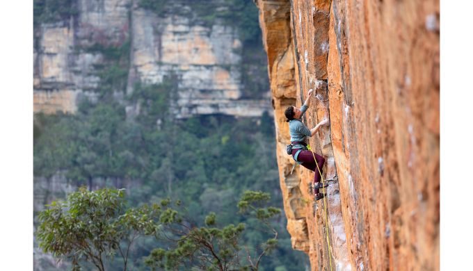 Female rock climber on orange sandstone sport route
