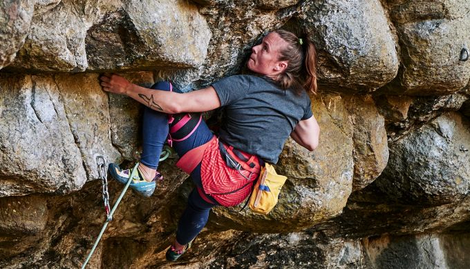 Woman climbing steep rock.