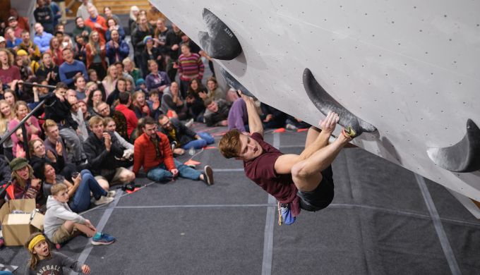 Competition climber on steep overhanging boulder problem.