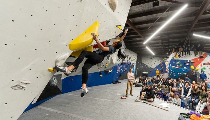 Female climbing in competition with crowd watching.