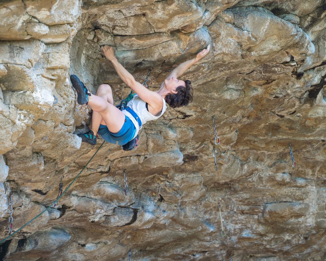 Woman climbing steep rock.