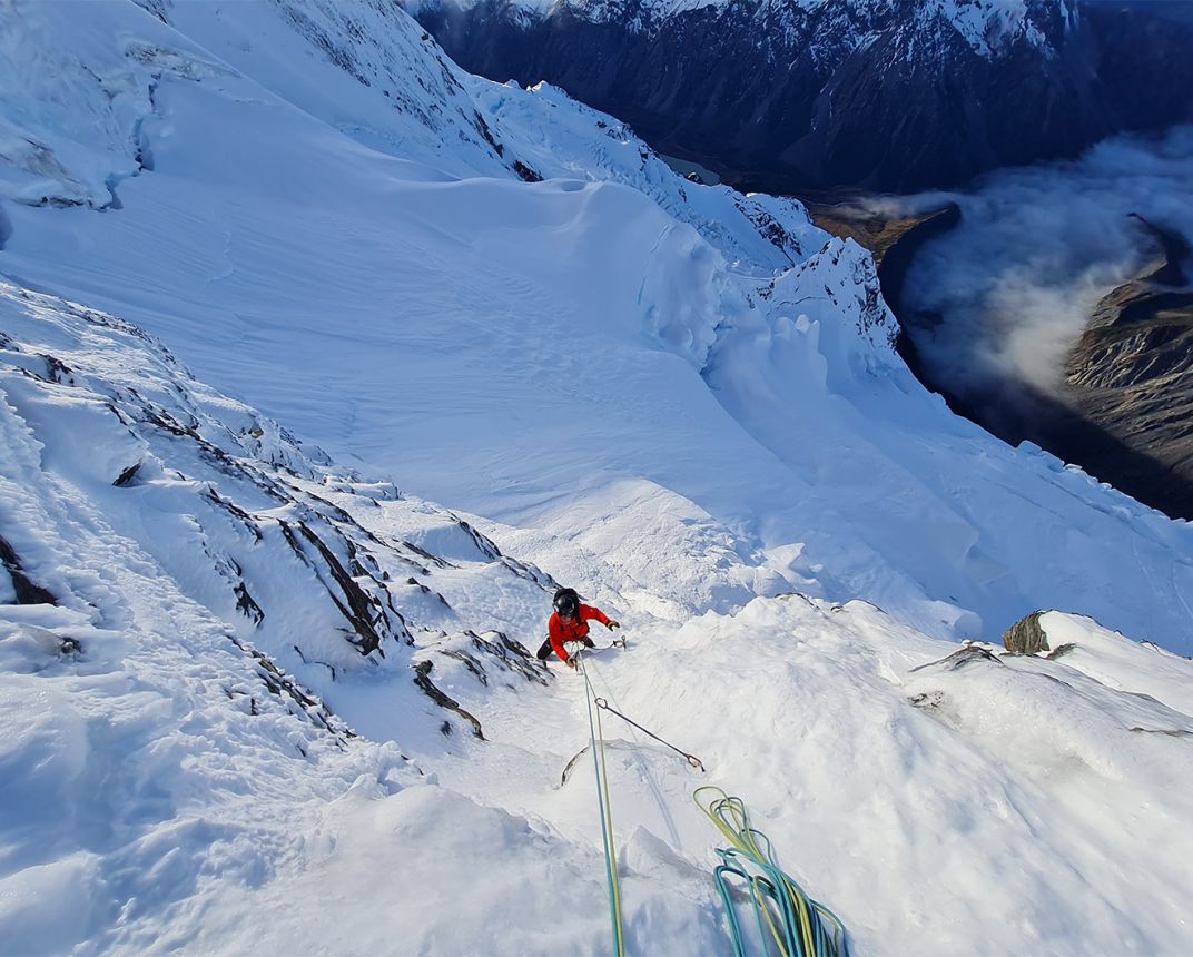 Alpine climber snow face valley of cloud