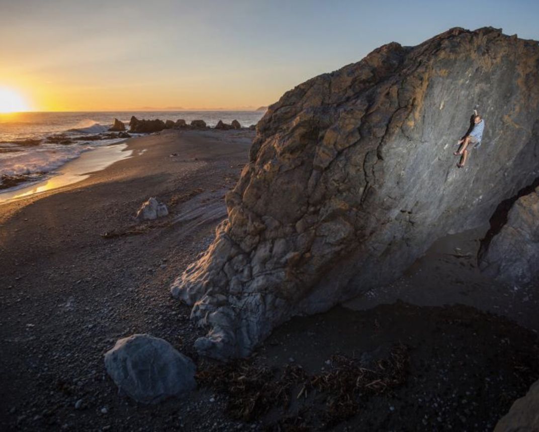 Climber on boulder at sunset.