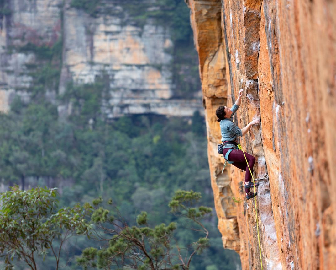 Female rock climber on orange sandstone sport route