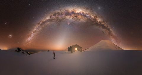 alpine hut on snow field under the milky way galaxy