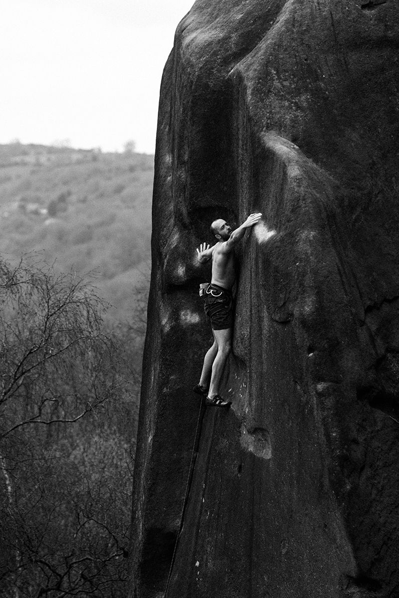 Black and white film photo of climber on dark rock