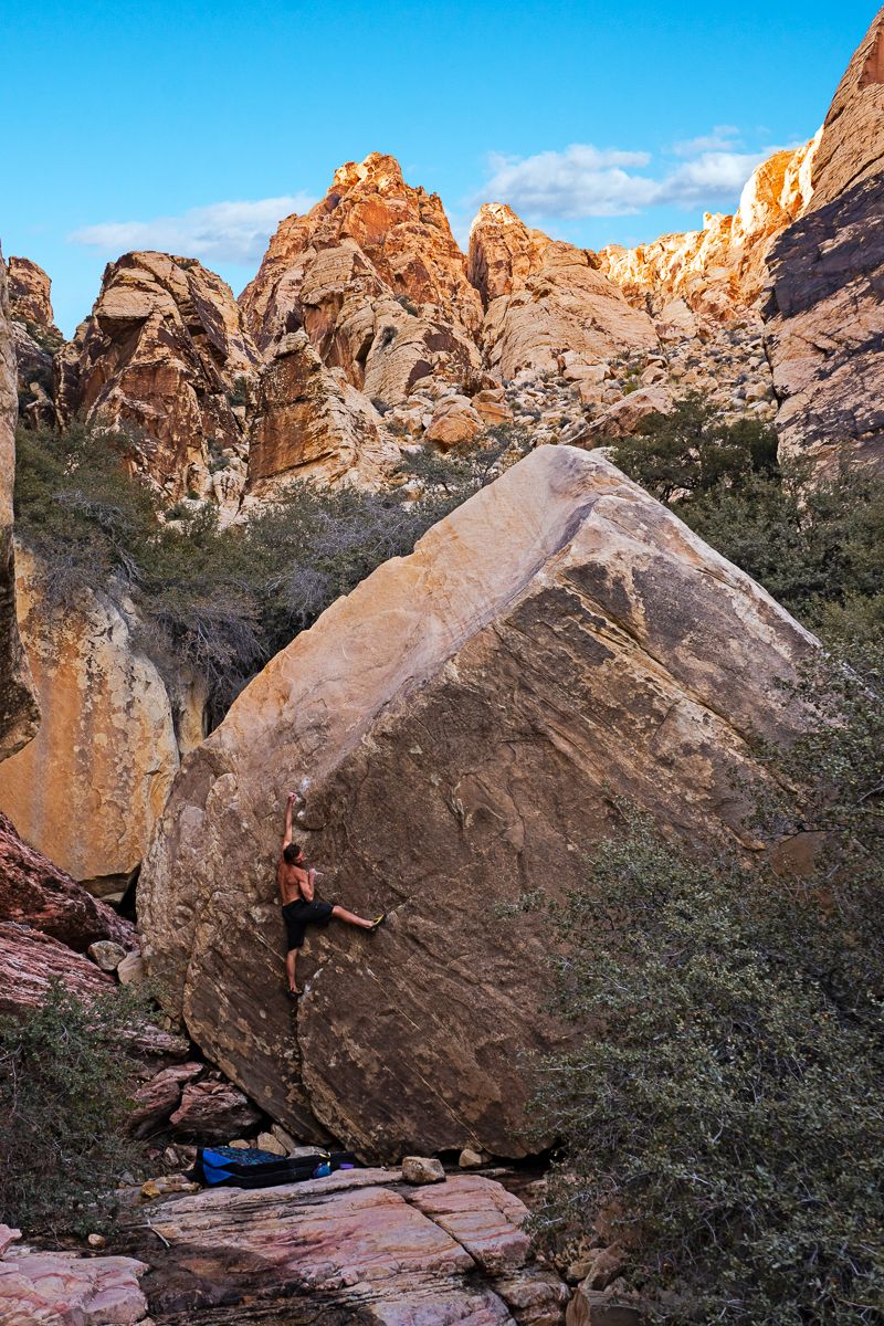 Boulderer ons andstone boulder in impressive canyon