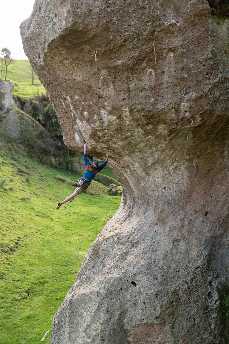 Climber swinging by one arm on steep rock