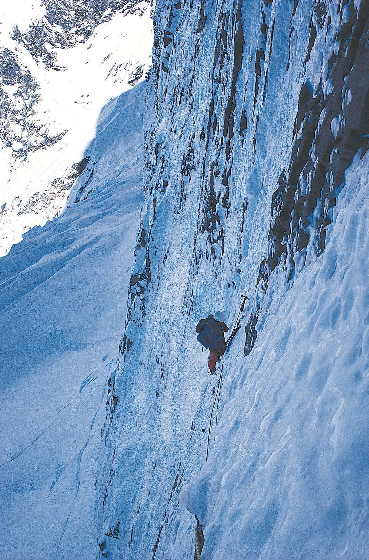 A climber on steep ice, part way up the face.