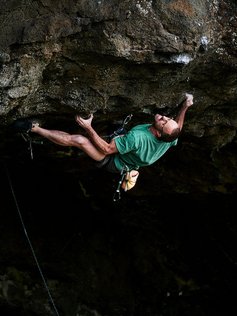 Rock climber grimaces on steep roof climb