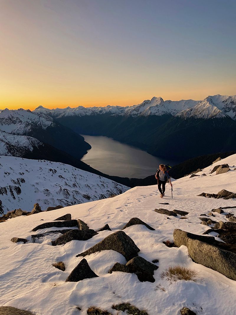Climber on snowy mountain at sunset