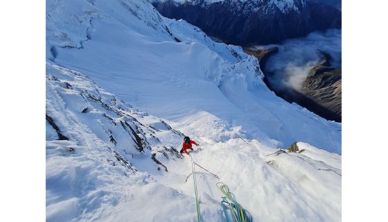 Alpine climber snow face valley of cloud