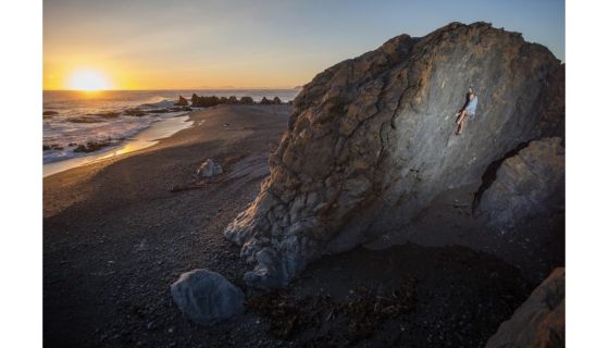 Climber on boulder at sunset.