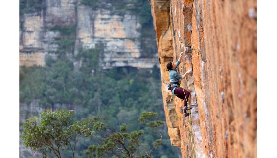 Female rock climber on orange sandstone sport route