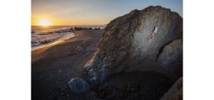 Climber on boulder at sunset.